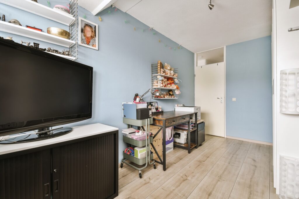 A room with a TV and desk that has toys and other things